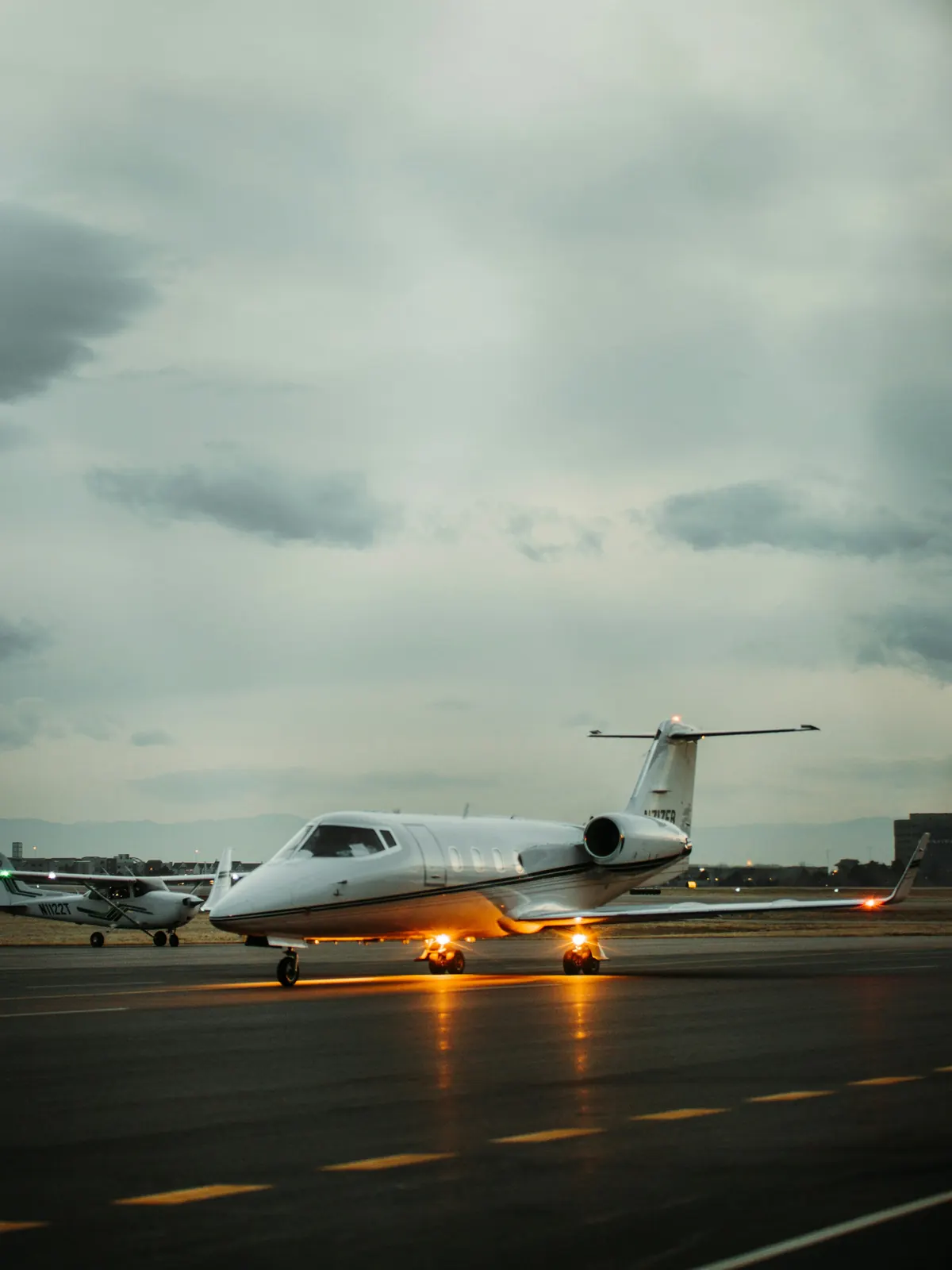 A small business jet on a wet ramp under a heavy sky