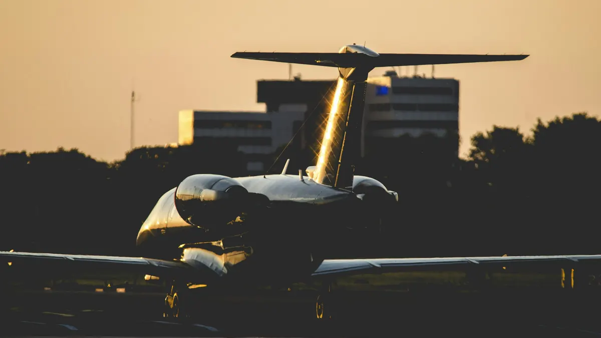 A business jet backlit by low golden light on the apron