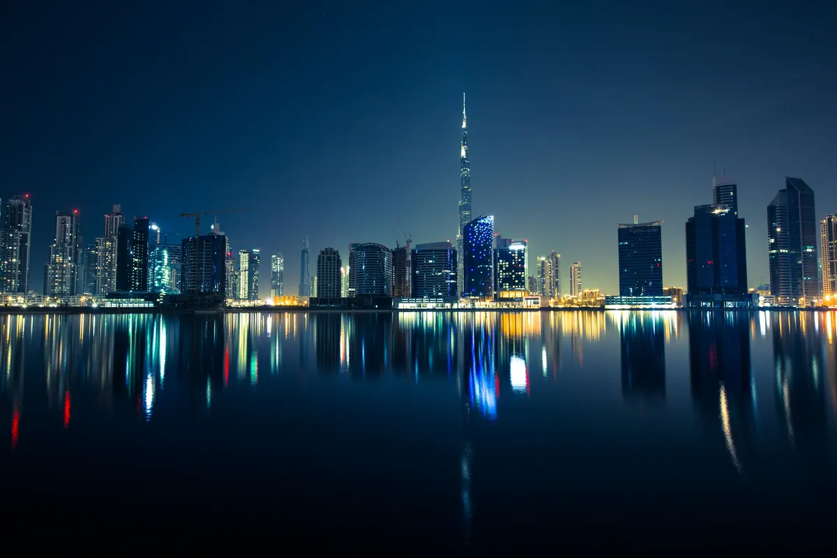 Dubai’s towers reflected in still water at night